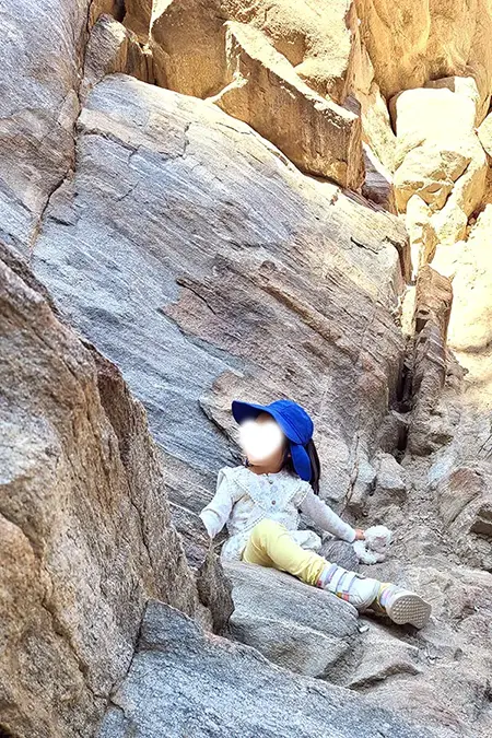 Child posing while sitting on a rock