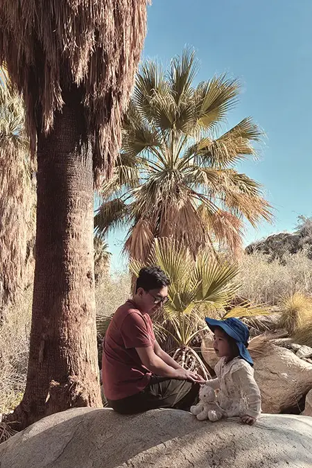 Child resting on a rock with their dad, Indian Canyon