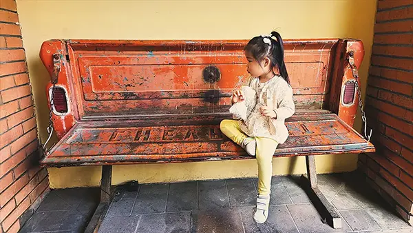 Child relaxing on a rustic red bench